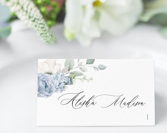 May include: A white place card with a blue and green floral design. The name "Alisha Madison" is written in black cursive script.