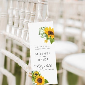 Op de afbeelding: Een witte kaart met een zonnebloemontwerp en de tekst "This seat is kindly reserved for the Mother of the Bride Elizabeth Anderson".