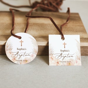 May include: Two baptism favor tags with a cross, floral design, and the text "Sophia's Baptism Thank You!" One tag is round and the other is square.