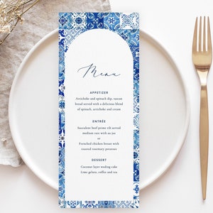 Puede incluir: Una tarjeta de menú de boda azul y blanca con un borde decorativo de azulejos azules y blancos. El menú incluye aperitivos, platos principales y postres. El texto de la tarjeta dice: "Menú", "Aperitivo", "Dip de alcachofa y espinacas, pan toscano servido con una deliciosa mezcla de espinacas, alcachofas y crema", "Plato principal", "Costilla de res suculenta servida a término medio con salsa o Pechuga de pollo francesa con papas asadas con romero", "Postre", "Pastel de bodas de coco Gelato de lima, café y té".