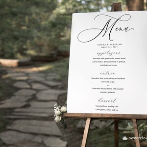 以下が含まれることがあります： 黒い書道文字で書かれた白い結婚式メニューの看板。看板には「メニュー」、「アリシャ＆サバティアン」、「2015年8月12日」、「アペタイザー」、「アーティチョークとほうれん草のディップ、トスカンブレッド、ほうれん草、アーティチョーク、クリームの美味しいブレンドを添えて」、「アントレ」、「ジューシーなプライムリブをミディアムレアで、オー・ジュを添えて、またはローストローズマリーポテトを添えたフレンチチキンブレスト」、「デザート」、「ココナッツレイヤーウェディングケーキ、ライムジェラート、コーヒー、紅茶」と書いてあります。
