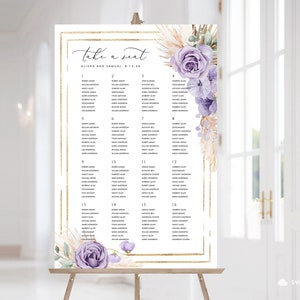 May include: A wedding seating chart with a gold frame and a floral design featuring purple flowers and dried pampas grass. The chart is titled "Take a Seat" and lists the names of guests and their assigned tables.