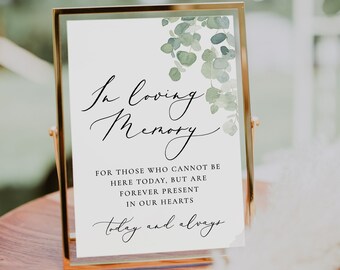 Può includere: Un cartello bianco con cornice dorata e un design acquerellato verde con foglie. Il cartello recita "In loving memory" e "For those who cannot be here today, but are forever present in our hearts today and always".