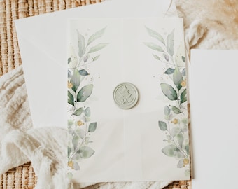 Op de afbeelding: Een witte envelop met een groene waszegel en een aquarelontwerp van groene bladeren en gouden accenten. De envelop ligt op een geweven bruine ondergrond.