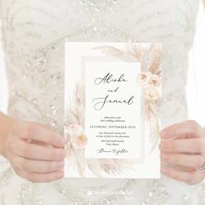 May include: Wedding invitation with a watercolor design featuring pampas grass and blush-colored flowers. The invitation reads "Alisha and Janual" and includes the date and time of the wedding, "Saturday, September 14th, two thousand twenty five at four o'clock in the afternoon." The location is listed as "Salt and Sand Garden, York, Maine." The invitation concludes with "Dance to follow."