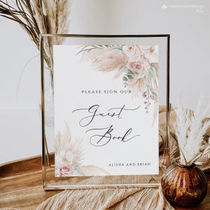 May include: A printable sign with a watercolor floral design featuring beige and pink flowers and greenery. The sign says "Please sign our Guest Book Alisha and Brian".