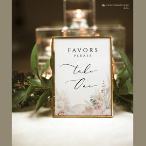 Puede incluir: Un cartel con marco dorado, fondo blanco y un dise&ntilde;o de acuarela de flores secas y vegetaci&oacute;n. El cartel dice "Favors Please Take One" en texto cursivo negro.