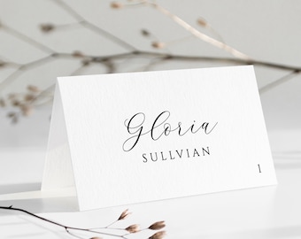 May include: White place card with the name "Gloria Sullivan" written in elegant cursive script. The number "1" is printed in the bottom right corner.