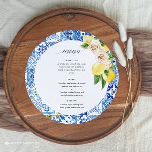 Może przedstawiać: Okrągła, biała karta menu z niebiesko-białą wzorzystą ramką. Karta menu zawiera akwarelowy rysunek cytryn i róż. Karta menu zawiera listę przystawek, dań głównych i deserów. Tekst na karcie menu brzmi: "menu", "appetizer", "artichoke and spinach dip, tuscon bread served with a delicious blend of spinach, artichoke and cream", "entree", "succulent beef prime rib served medium rare with au jus or frenched chicken breast with roasted rosemary potatoes", "dessert", "coconut layer wedding cake lime gelato, coffee and tea".