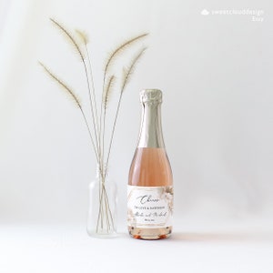 May include: A small bottle of champagne with a gold and white label that says "Cheers to love and happiness" with the names "Alisha and Michael" and the date "May 12, 2019".