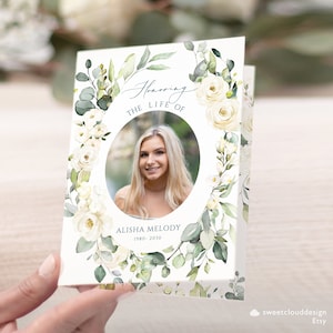 Könnte beinhalten: Eine weiße und grüne Blumen-Gedenkkarte mit einem Foto einer Frau in einem Kreis. Der Text lautet "Honoring the Life of Alisha Melody 1980-2030".