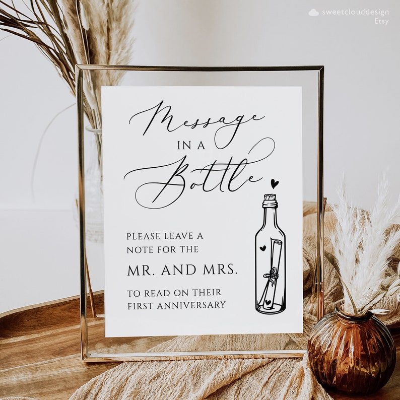 May include: A white sign with black text that reads "Message in a Bottle" with a drawing of a bottle with a rolled up note inside. The sign also says "Please leave a note for the Mr. and Mrs. to read on their first anniversary."