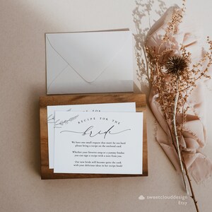 May include: A white card with black text that reads "Recipe for the Bride". The card has a floral design in the top left corner and instructions for guests to bring a recipe for the bride.