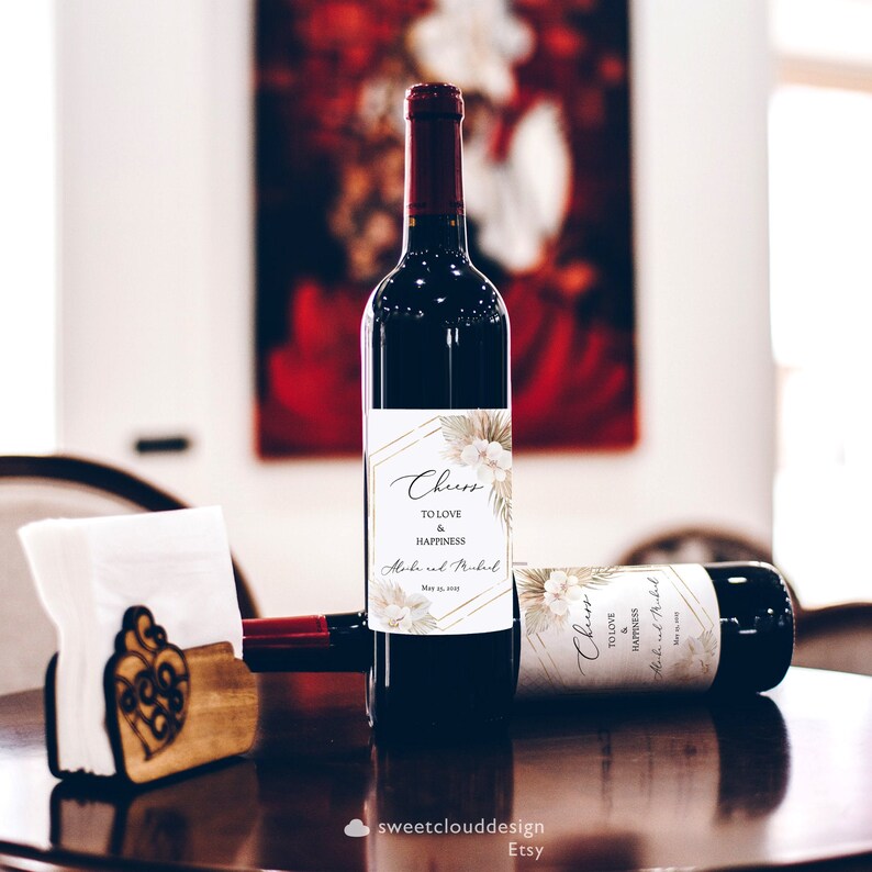 May include: Two wine bottles with personalized labels featuring a tropical leaf design and the text "Cheers to Love & Happiness" with the names "Alock and Rubul" and the date "May 13, 2017".