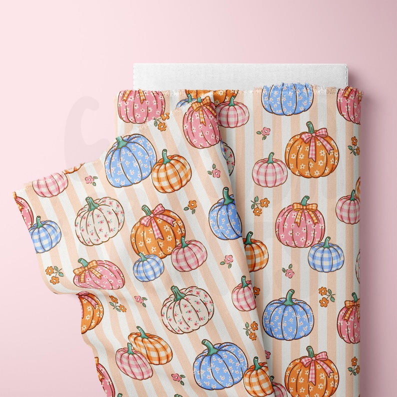May include: A roll of fabric featuring a repeating pattern of pumpkins in various colors, including blue, pink, and orange, with floral details. The pumpkins are set against a backdrop of vertical peach stripes.