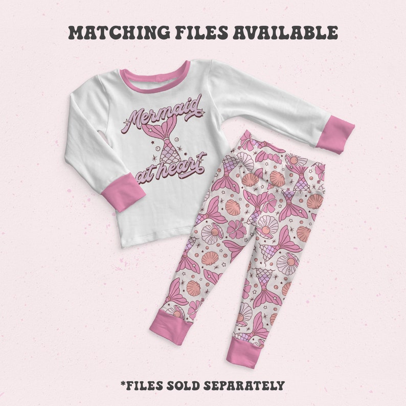 May include: White long-sleeved shirt with pink trim and a pink mermaid graphic that says "Mermaid at heart". Matching pink pants with a mermaid tail and seashell pattern.