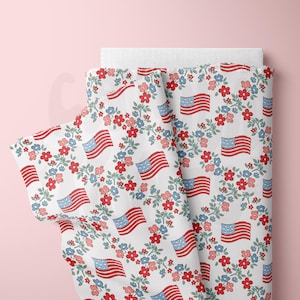 May include: White fabric with a repeating pattern of red, white, and blue American flags surrounded by wreaths of blue, red, and pink flowers.