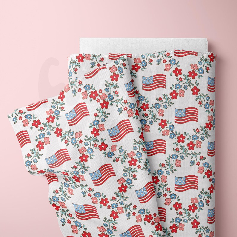 May include: White fabric with a repeating pattern of red, white, and blue American flags surrounded by wreaths of blue, red, and pink flowers.