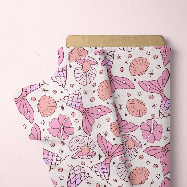 May include: Pink fabric with a repeating pattern of mermaids, seashells, and stars. The mermaids are pink and have a tail with scales. The seashells are pink and white. The stars are white.