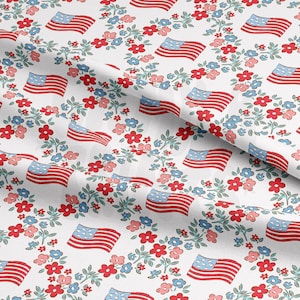 May include: White fabric with a repeating pattern of red, white, and blue American flags surrounded by small red, blue, and green flowers.