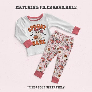 Pode incluir: Conjunto de pijama branco e coral de manga comprida. A parte superior apresenta um gr&aacute;fico de fantasma com as palavras "Spooky Babe". As cal&ccedil;as t&ecirc;m um padr&atilde;o repetido de fantasmas, arco-&iacute;ris e doces. O texto "Matching Files Available" est&aacute; no topo.