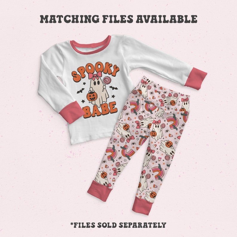 Pode incluir: Conjunto de pijama branco e coral de manga comprida. A parte superior apresenta um gr&aacute;fico de fantasma com as palavras "Spooky Babe". As cal&ccedil;as t&ecirc;m um padr&atilde;o repetido de fantasmas, arco-&iacute;ris e doces. O texto "Matching Files Available" est&aacute; no topo.