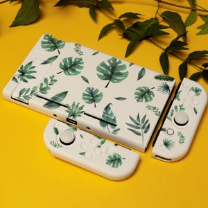 May include: White gaming console and controllers with a green tropical leaf pattern. The console and controllers are set against a yellow background with green vines. The design features various green leaves.