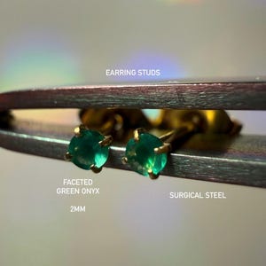 May include: A pair of 2mm earring studs featuring faceted green onyx stones set in surgical steel. The text on the image reads EARRING STUDS, FACETED GREEN ONYX, 2MM, and SURGICAL STEEL. The earrings are held by metal tweezers.