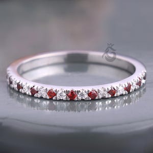 May include: A silver band ring with a row of small red and white gemstones.