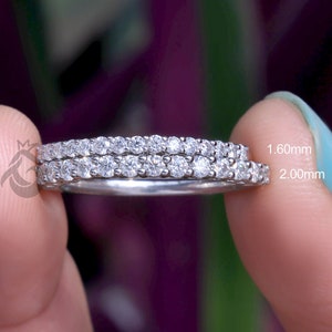 Może przedstawiać: Dwa srebrne pierścionki wieczności z małymi, przezroczystymi diamentami. Pierścionki mają szerokość 1,60 mm i 2,00 mm.