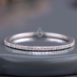 May include: A thin silver band with a row of small, clear diamonds set around the entire circumference.
