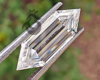 May include: A marquise-cut gemstone with a step-cut facet pattern held by metal tweezers. The clear, colorless stone features elongated parallel facets running along its length, tapering to sharp points at both ends, reflecting light with high clarity.