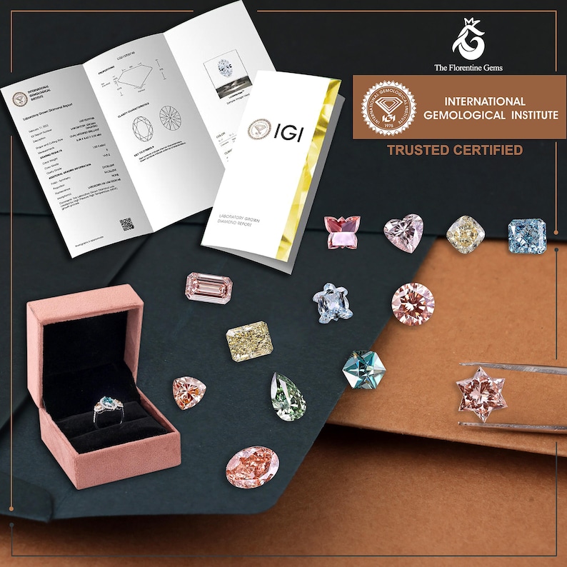 May include: A collection of loose, multi-colored faceted gemstones in various shapes including star, heart, butterfly, and turtle, alongside a ring in a pink velvet box and an International Gemological Institute laboratory report document.