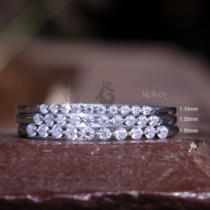 Puede incluir: Tres anillos de plata con una fila de pequeños diamantes en cada uno. Los anillos están apilados uno encima del otro, con el anillo más grande en la parte inferior y el anillo más pequeño en la parte superior. Los anillos están etiquetados con sus tamaños: 1,10 mm, 1,30 mm y 1,50 mm. NLR-01