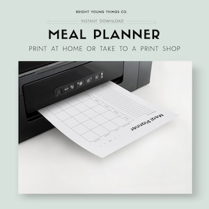 May include: A black and white printable meal planner with the text "Meal Planner" printed on the page. The planner is being printed from a black printer.