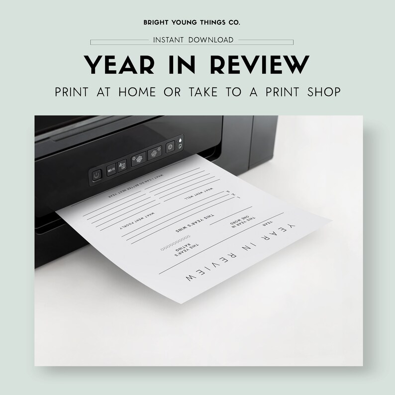 May include: A black printer printing a white "Year in Review" printable sheet. The sheet has prompts for reflection, including "This Year's Wins" and "What Went Well." The text "Bright Young Things Co." and "Instant Download" are at the top.