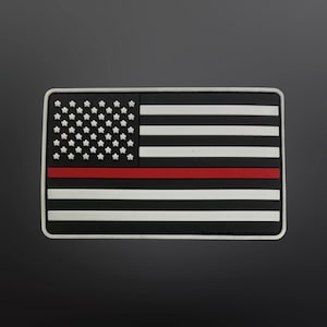 May include: A black and white American flag patch with a single red stripe across the middle. The patch is made of a rubber-like material.