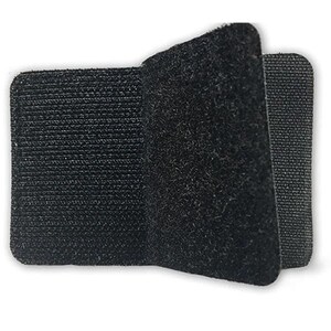 Op de afbeelding: Een zwarte klittenband sluiting, ook wel bekend als Velcro, met een ruwe en een gladde kant. De sluiting is gemaakt van een zacht, flexibel materiaal.