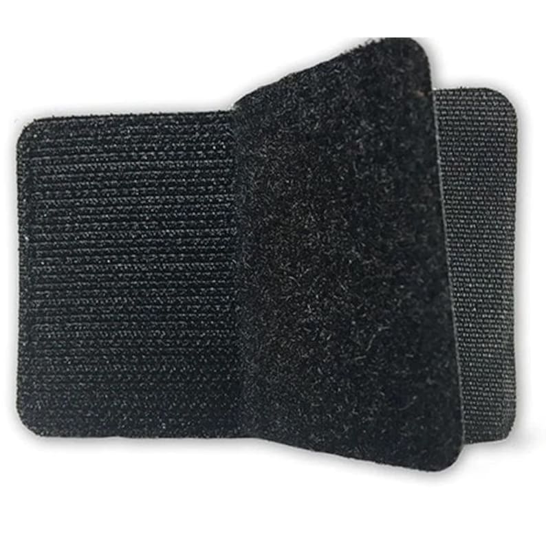 Op de afbeelding: Een zwarte klittenband sluiting, ook wel bekend als Velcro, met een ruwe en een gladde kant. De sluiting is gemaakt van een zacht, flexibel materiaal.