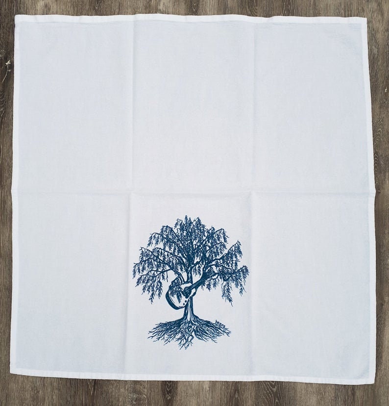 May include: White tea towel with a blue embroidered design of a tree with a guitar in its branches.