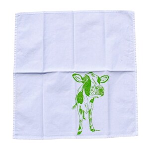 Puede incluir: Pa&ntilde;o de cocina de algod&oacute;n blanco con una ilustraci&oacute;n verde de una vaca. La vaca est&aacute; representada en un estilo sencillo, de l&iacute;nea. El pa&ntilde;o es cuadrado y tiene un borde cosido. La ilustraci&oacute;n de la vaca est&aacute; situada en el centro inferior del pa&ntilde;o.