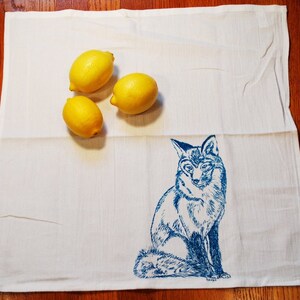 Puede incluir: Pa&ntilde;o de cocina blanco con una ilustraci&oacute;n de zorro azul y tres limones amarillos. El zorro est&aacute; representado con detalle. Los limones a&ntilde;aden un toque de color brillante.