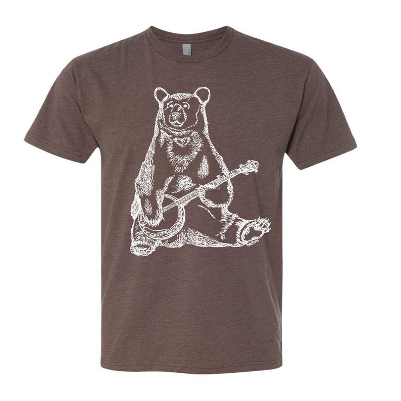 May include: A brown t-shirt with a white illustration of a bear playing a banjo.