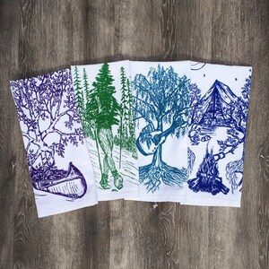 Pode incluir: Conjunto de cinco toalhas de cozinha com designs inspirados na natureza. As toalhas s&atilde;o brancas com ilustra&ccedil;&otilde;es azuis, verdes e roxas de &aacute;rvores, uma canoa, uma fogueira e um viol&atilde;o.