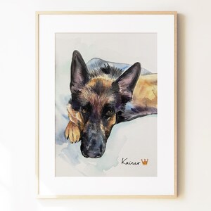 May include: A framed watercolor painting of a German Shepherd dog looking forward with black and tan fur. The name Kaiser is written in black script below the dog, accompanied by a small orange crown icon, all set against a light background.
