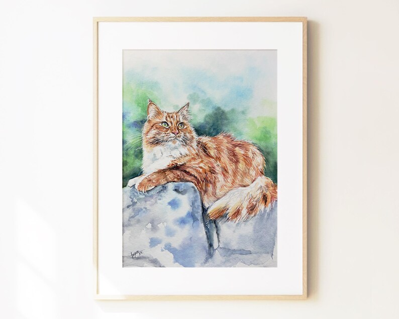 May include: A framed watercolor painting depicting a long-haired ginger and white cat resting on a large, cool-toned stone. The cat has green eyes and is looking toward the upper right. The background features soft, blended washes of green and blue.