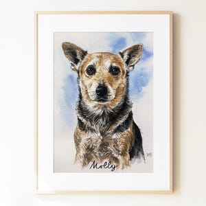 May include: A framed watercolor portrait of a brown and black dog with pointed ears, set against a soft blue wash background. The name Molly is written in black cursive script at the bottom center of the artwork, which is encased in a light wood frame.