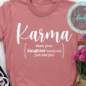 Op de afbeelding: Een roze T-shirt met de tekst "Karma" en een definitie: "wanneer je dochter blijkt net als jij te zijn".