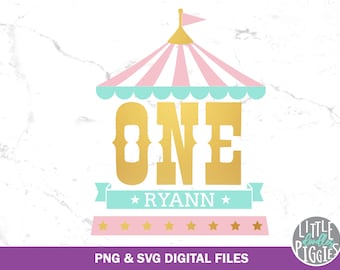 以下が含まれることがあります： ピンクとブルーのサーカステントに、金の「ONE」と「RYANN」という名前が書かれています。テントの名前の両側に星があります。名前の下には金の星が5つあります。