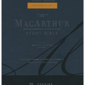 Puede incluir: La Biblia de Estudio de MacArthur, Segunda Edición, en una cubierta de cuero azul oscuro con letras doradas. La cubierta presenta el título "The MacArthur Study Bible" y "Second Edition". La Biblia es parte de la colección Premier y está hecha con papel europeo y tres cintas de satén.